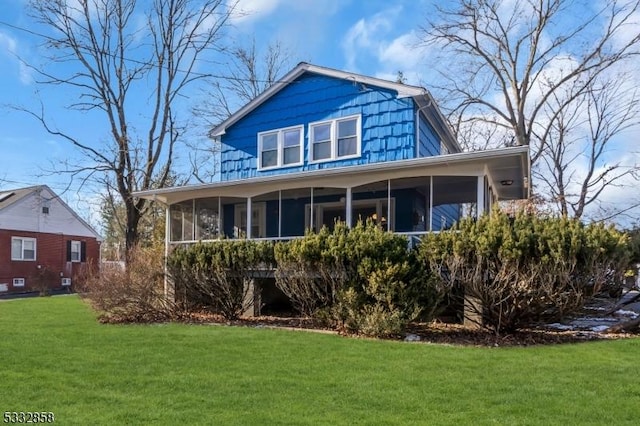 back of property with a lawn and a sunroom