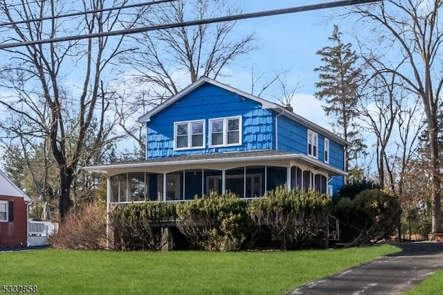 view of front facade with a front lawn and a sunroom