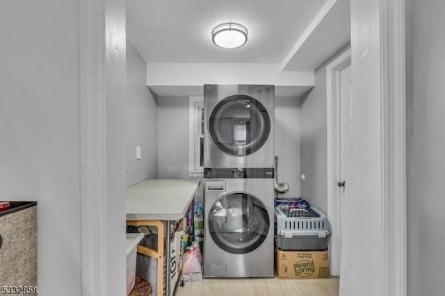 laundry area with stacked washer and clothes dryer and light hardwood / wood-style floors