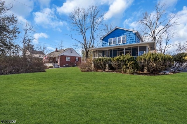 rear view of property with a yard and a sunroom