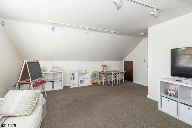 recreation room featuring track lighting, vaulted ceiling, and dark carpet