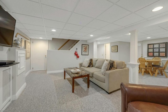 carpeted living room featuring decorative columns and a drop ceiling