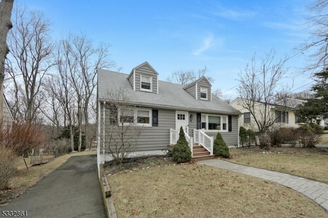 cape cod house featuring a front lawn