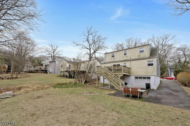 rear view of house with a yard, a garage, and a wooden deck