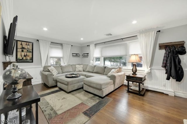 living room featuring a healthy amount of sunlight, dark wood-type flooring, and crown molding