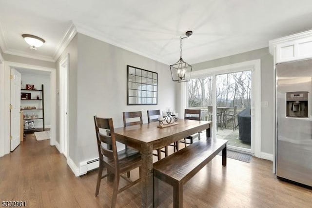 dining room featuring hardwood / wood-style floors, a chandelier, baseboard heating, and crown molding