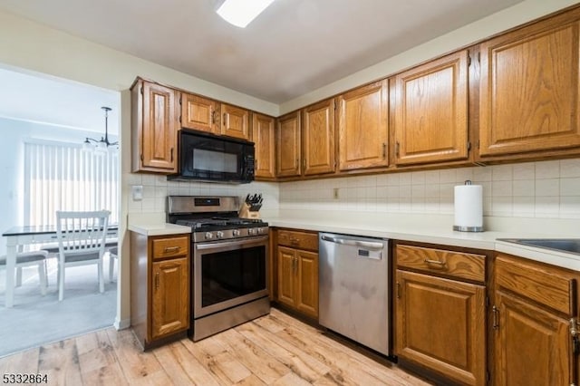 kitchen featuring decorative backsplash, light hardwood / wood-style flooring, stainless steel appliances, and a chandelier