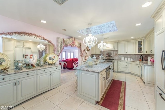 kitchen with light tile patterned floors, an island with sink, a skylight, backsplash, and pendant lighting