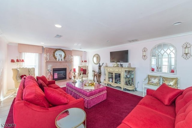 tiled living room featuring a premium fireplace, a wealth of natural light, and crown molding