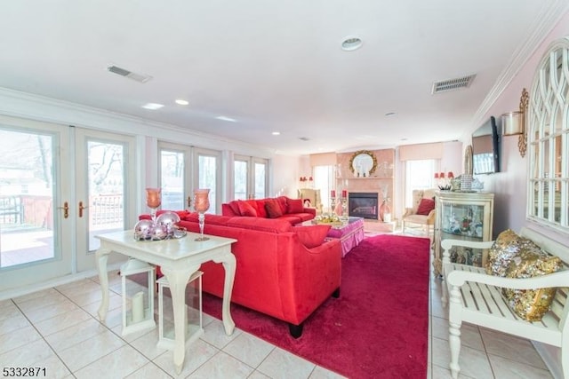 living room with a large fireplace, crown molding, french doors, and light tile patterned floors