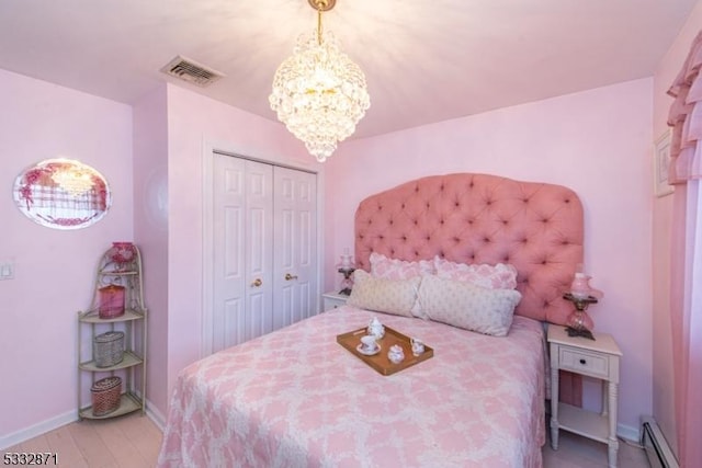 bedroom with a closet, an inviting chandelier, baseboard heating, and light hardwood / wood-style flooring