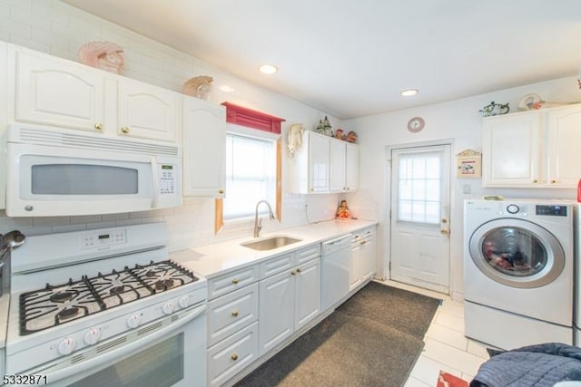 kitchen featuring white appliances, sink, washer / clothes dryer, and white cabinetry