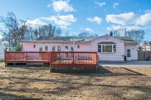 back of property with a deck and a lawn