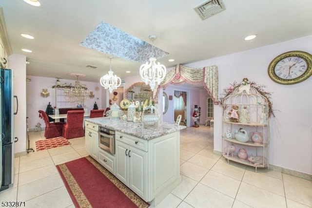 kitchen featuring white cabinets, stainless steel oven, light tile patterned floors, hanging light fixtures, and a kitchen island