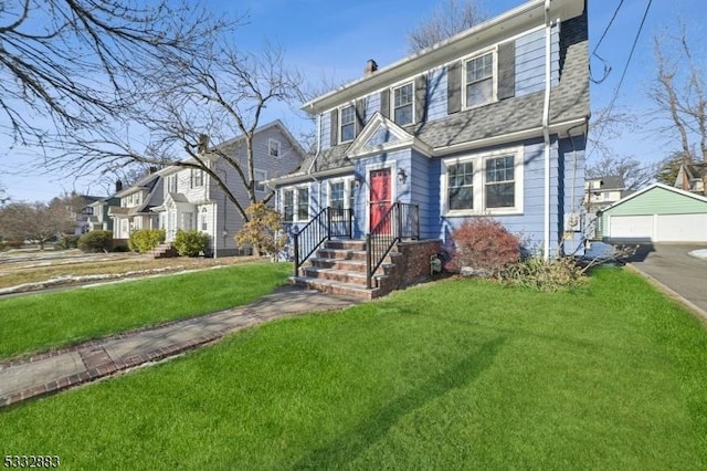 view of front of home featuring a garage, an outdoor structure, and a front lawn