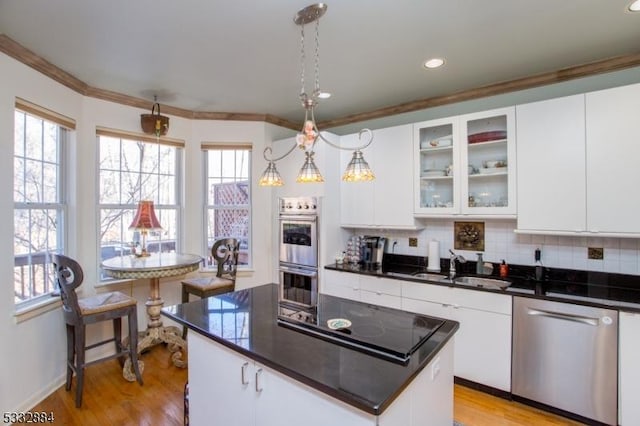 kitchen featuring appliances with stainless steel finishes, pendant lighting, a kitchen island, white cabinets, and sink