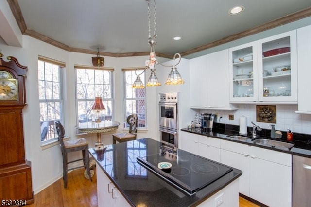 kitchen with stainless steel appliances, sink, decorative light fixtures, white cabinets, and light hardwood / wood-style floors