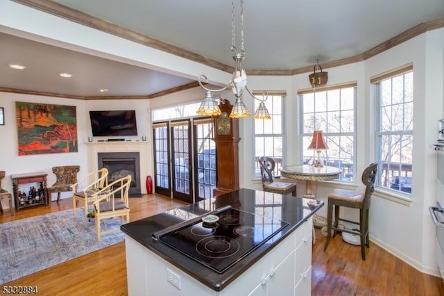 kitchen with decorative light fixtures, white cabinetry, light hardwood / wood-style flooring, and black electric cooktop