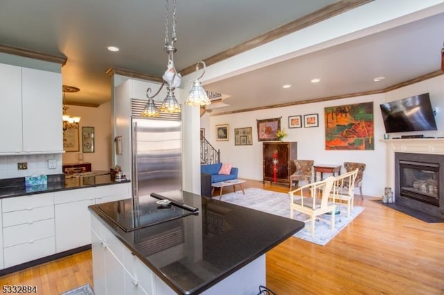 kitchen featuring hanging light fixtures, a center island, stainless steel built in refrigerator, decorative backsplash, and white cabinets