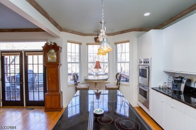 kitchen with white cabinets, hanging light fixtures, wood-type flooring, and double oven