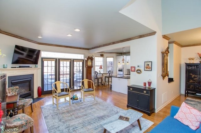 living room featuring a notable chandelier, light hardwood / wood-style floors, and crown molding