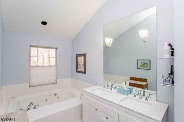 bathroom featuring a relaxing tiled tub, vaulted ceiling, and vanity