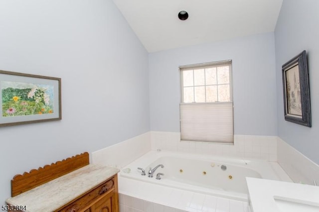 bathroom featuring a relaxing tiled tub and vanity