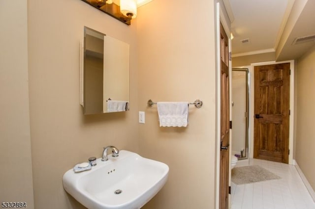 bathroom featuring toilet, a shower with shower door, crown molding, and sink