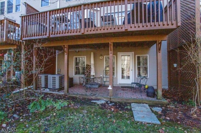 entrance to property with a patio, a deck, and cooling unit