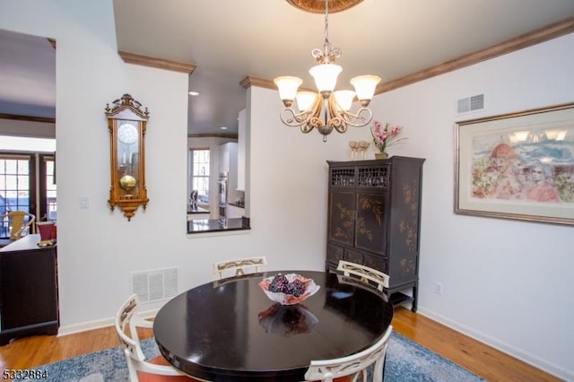 dining area featuring light wood-type flooring, crown molding, and a chandelier