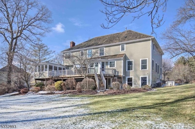 snow covered property with a deck, a sunroom, and a yard