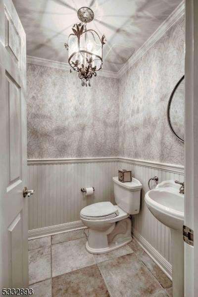 bathroom with toilet, ornamental molding, and an inviting chandelier