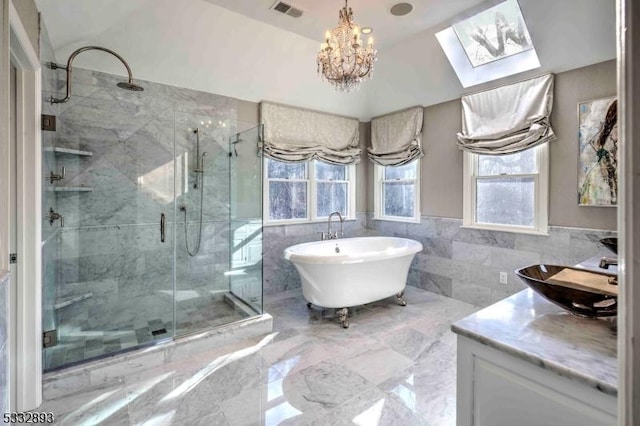 bathroom with a notable chandelier, independent shower and bath, tile walls, lofted ceiling with skylight, and vanity