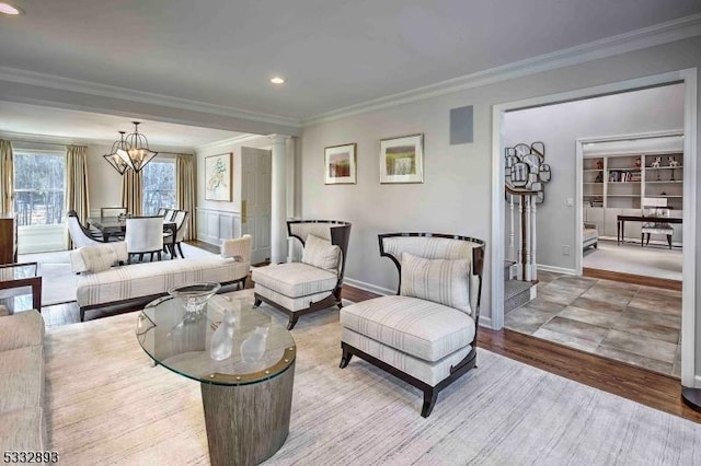 living room featuring a notable chandelier, crown molding, light hardwood / wood-style floors, and decorative columns