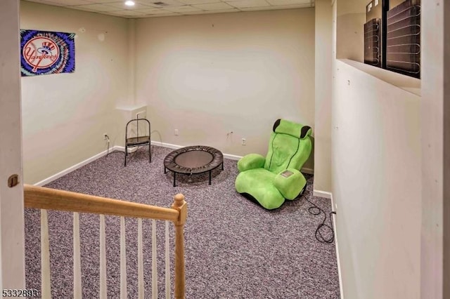 living area featuring carpet and a paneled ceiling