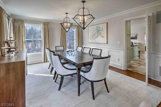 dining space with light hardwood / wood-style floors, a chandelier, and ornamental molding