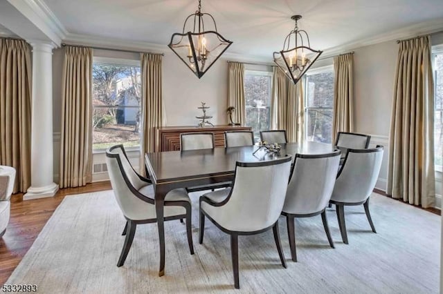 dining room with an inviting chandelier, plenty of natural light, crown molding, and light hardwood / wood-style flooring