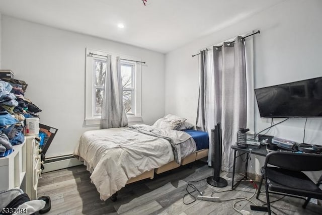 bedroom with wood-type flooring and a baseboard heating unit