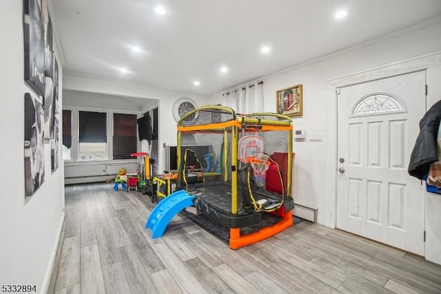 playroom featuring crown molding, a baseboard radiator, and light hardwood / wood-style flooring