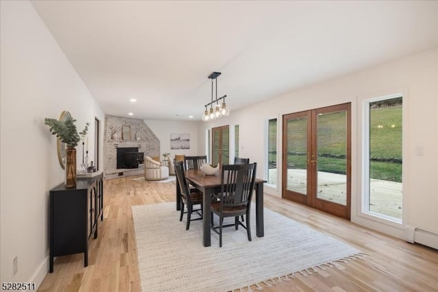 dining space with light wood-type flooring, plenty of natural light, a baseboard heating unit, and french doors