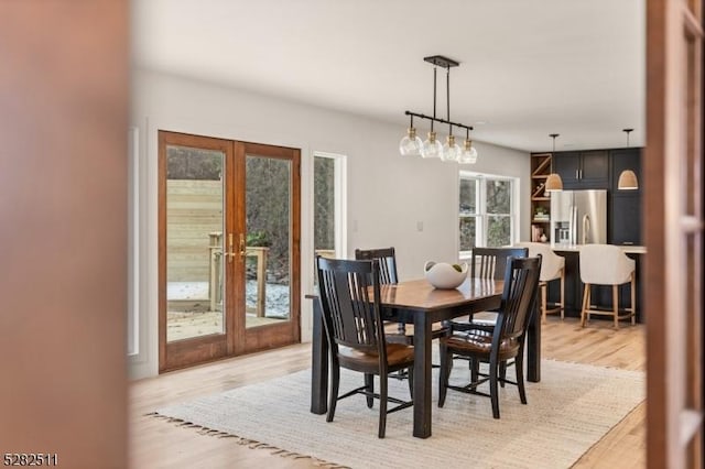 dining area with light wood-type flooring, a healthy amount of sunlight, and french doors