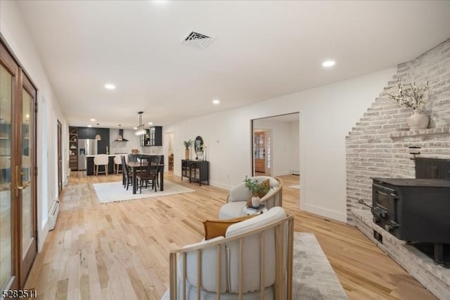 living room featuring a wood stove and light hardwood / wood-style flooring