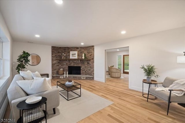 living room featuring a brick fireplace and light hardwood / wood-style floors