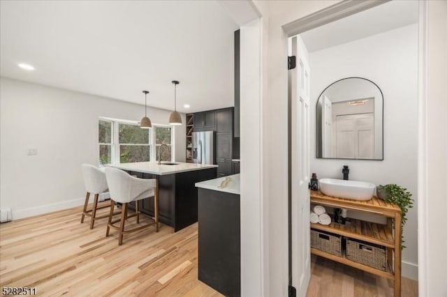 kitchen with sink, a kitchen breakfast bar, stainless steel fridge with ice dispenser, and an island with sink