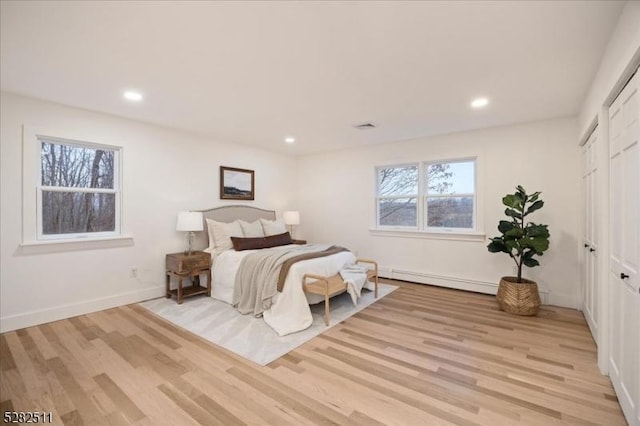 bedroom featuring light hardwood / wood-style flooring, a closet, and a baseboard radiator