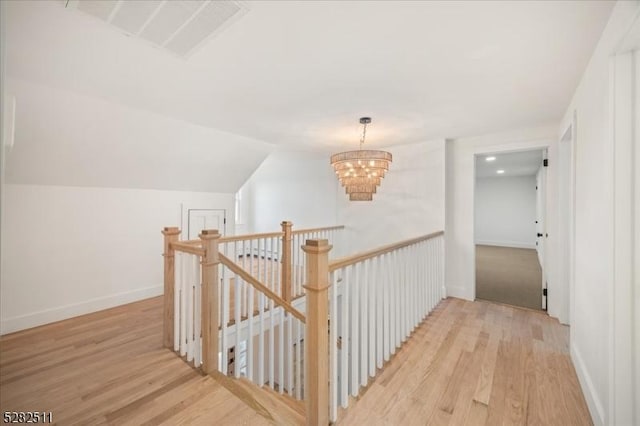 hallway featuring vaulted ceiling, an inviting chandelier, and light hardwood / wood-style floors