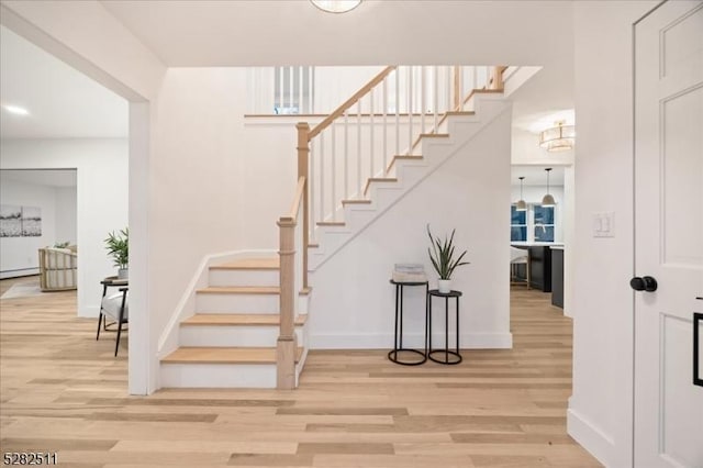 stairs with wood-type flooring and a baseboard radiator