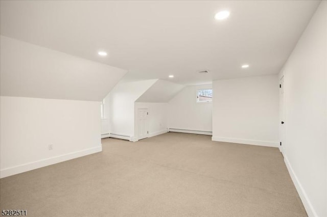 additional living space with a baseboard heating unit, lofted ceiling, and light colored carpet