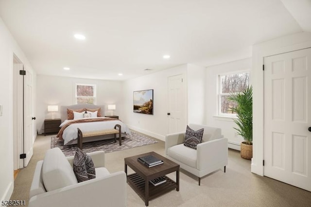 bedroom with a baseboard heating unit and light carpet