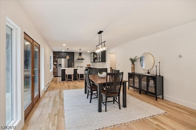 dining area featuring a baseboard radiator, a notable chandelier, and light wood-type flooring